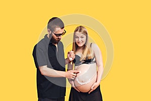 the guy draws with cream emoji on the belly of his pregnant wife on a yellow background