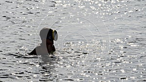 A guy dressed with a diving mask in the sea. A young man with a diving mask