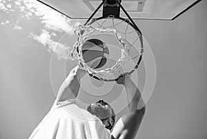 guy dunking basketball ball through net ring with hands, winning
