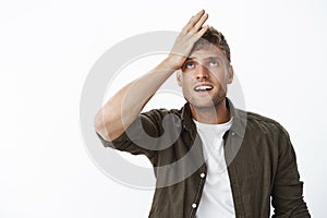 Guy feeling upset and regret as forgetting something, cannot recall information holding palm on forehead looking up