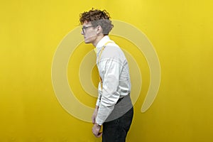 guy in festive outfit with bad posture on yellow isolated background, nerd student hunchbacked in shirt