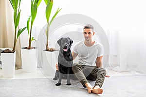 Guy freelancer with his dog labrador playing at home
