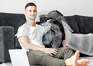 Guy freelancer with his dog labrador playing at home