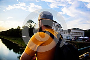 Guy in front of blue sky at evening time admire landscape. Enjoy pleasant moment. Man in cap enjoy sunset while stand on