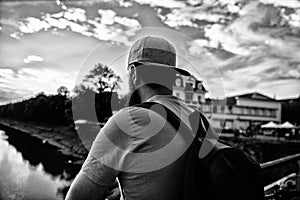 Guy in front of blue sky at evening time admire landscape. Enjoy pleasant moment. Man in cap enjoy sunset while stand on