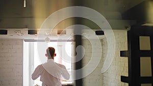 The guy gets dressed standing in front of a large bright window. Shooting from behin