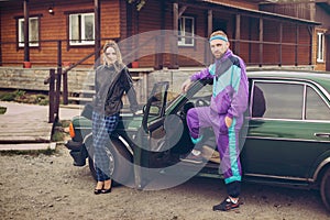 Guy and girl in clothes of the nineties, next to the old car