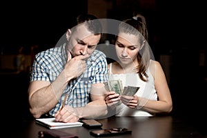 Guy and the girl are counting the money and looking thoughtfully