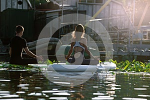 Guy with girl doing yoga on water