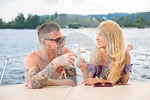 A guy with a girl is drinking champagne on a yacht.