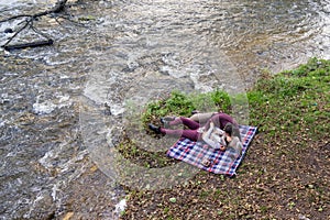 a guy and a girl are drinking tea near the river