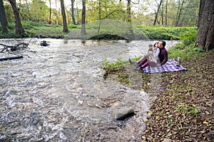 a guy and a girl are drinking tea near the river