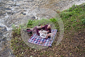 a guy and a girl are drinking tea near the river