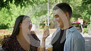 A guy and a girl eat ice cream in a city park