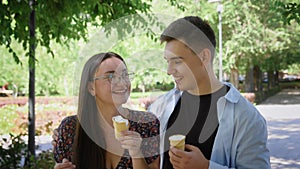 A guy and a girl eat ice cream in a city park