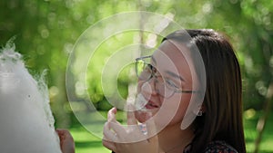 A guy and a girl in eating cotton candy in a city park