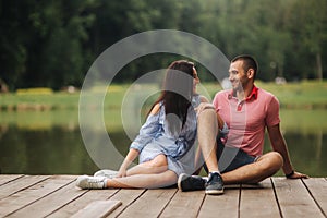 A guy and a girl enjoy each other in a romantic atmosphere, sits on the pier