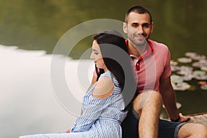 A guy and a girl enjoy each other in a romantic atmosphere, sits on the pier