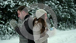 Guy and girl in the forest, drinking tea in winter