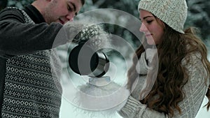 Guy and girl in the forest, drinking tea in winter