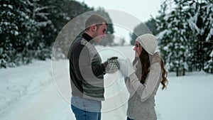 Guy and girl in the forest, drinking tea in winter