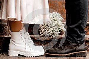 A guy and a girl go hand in hand down the street. girl in a dress and coat, a guy in a suit. wedding outfit