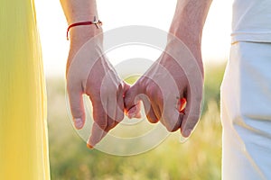 A guy and a girl are holding hands with littles in nature. Summer field and love of two people in love, romance and walks