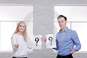 A guy and a girl, holding a leaf with a question mark with a questioning look.