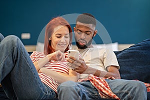 Guy and girl hug using phone. Woman and man watching videos, news from smartphone, smiling, laughing