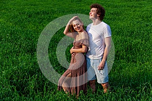 A guy and a girl are hugging on a green field