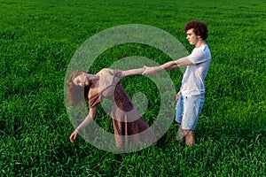 A guy and a girl are hugging on a green field