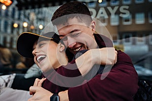 Guy and a girl are hugging at a table in a outdoor cafe.