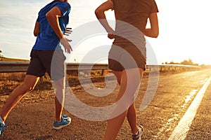 A guy and a girl jog along the road at sunset in nature.