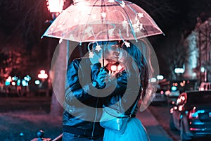 Guy and girl kissing under an umbrella