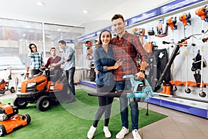 A guy and a girl are posing on the camera with a leaf blower.