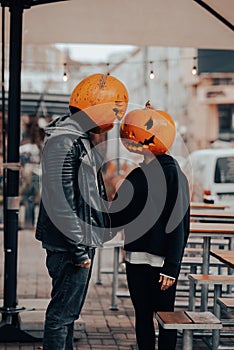 Guy and girl with pumpkin heads look at each other