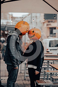 Guy and girl with pumpkin heads look at each other