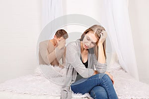 The guy with the girl sit upset on the bed
