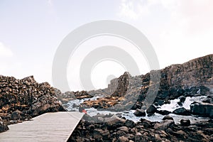 A guy and a girl are sitting embracing on a bridge near Ehsaraurfoss Waterfall, Ehsarau River, National Park