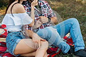 sexual attraction. a guy and a girl are sitting on a plaid veil on the grass, hugging and kissing. a man in a plaid shirt and jean