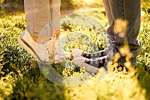 A guy and a girl stand opposite each other on the green grass, their feet are shod in sneakers, a summer meeting, horizontal image