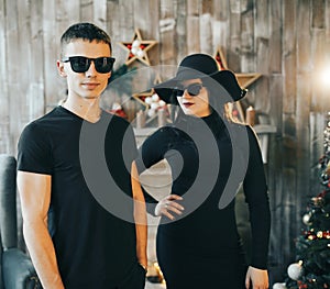 Guy and girl standing in front of a fireplace near a Christmas tree