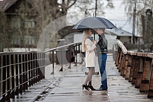 Guy and the girl under an umbrella on the bridge