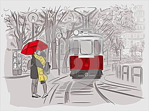 The guy and the girl are waiting for the tram under the umbrella. Cityscapes of Vienna photo