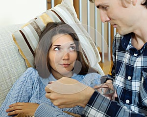 Guy giving sirup to unwell girlfriend