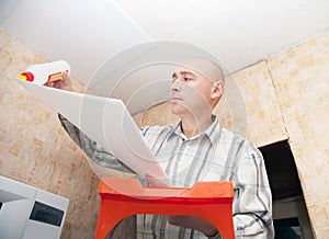 Guy glues ceiling the tile