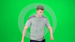 Guy goes and dances, smiles and rejoices on a green screen, Chroma Key. Side view