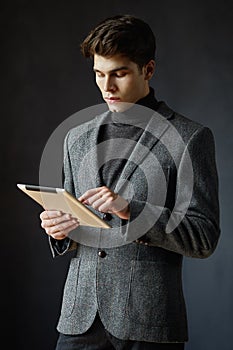 Guy with hairstyle holding tablet and working on it