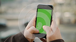 Guy hands touching cellphone green screen. Man texting by mock up phone outside