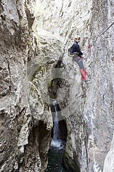 Guy hanging from the rope with a waterfall